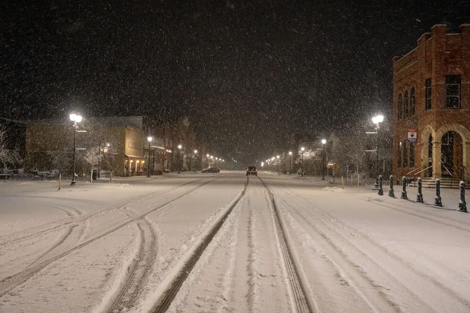 A quiet snow-covered street in Wabasha, MN at night, illuminated by street lights.